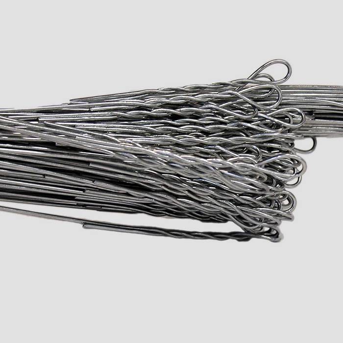 Several pieces of galvanized single loop bale ties on white background.