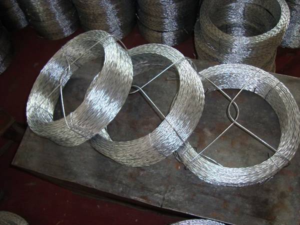 There is a coil of stainless steel twisted wire on the white ground.
